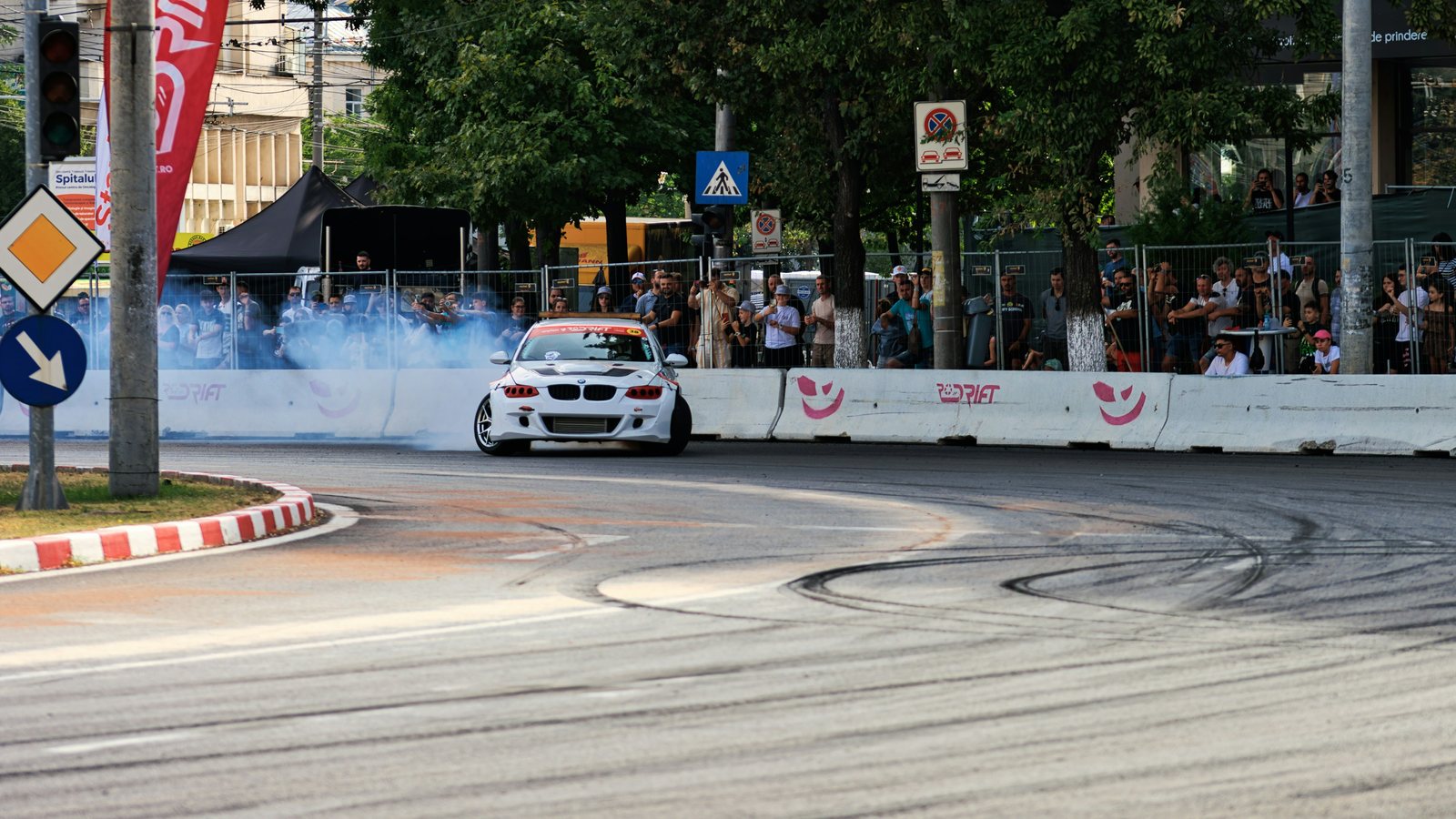 A car mid-drift on a street circuit, smoke trailing, skid marks on the tarmac